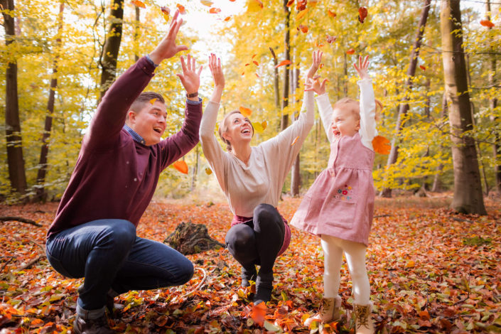 family tossing autumn leaves up in the air