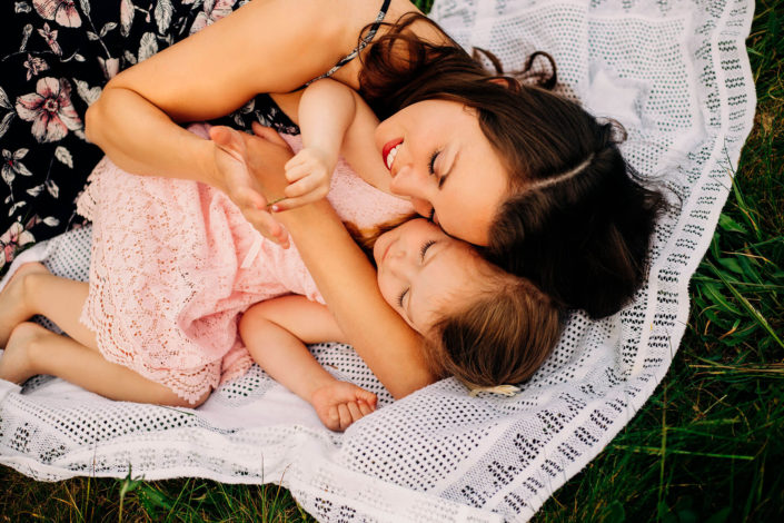 mom and daughter cuddling in a field