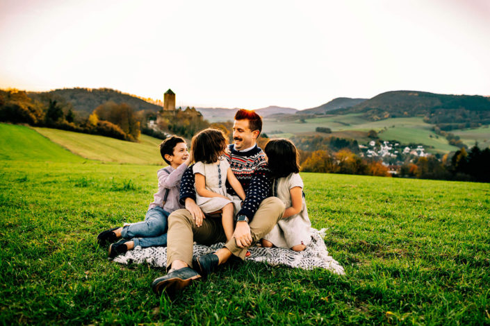 Dad and kids laughing together against a German castle background